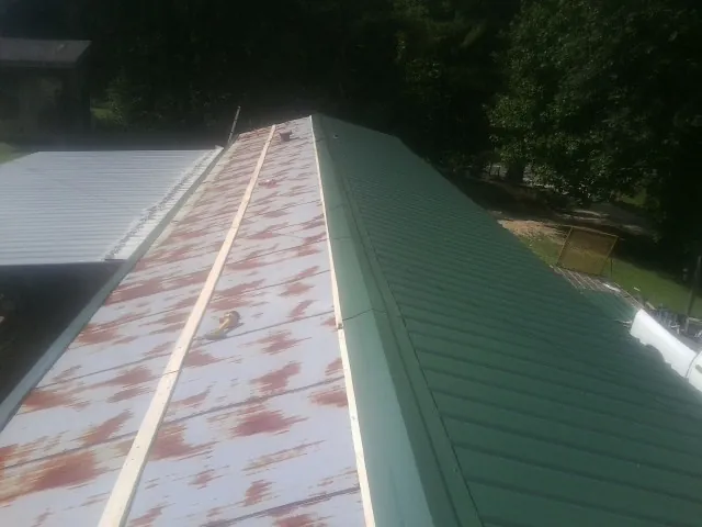 Old rusted panels beside newly installed green metal roofing — Wind Damage Roof Repair by Roofing Brothers in Elko