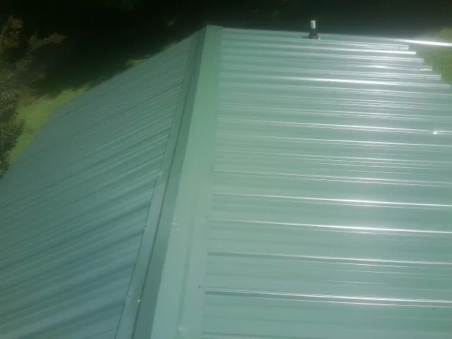 New green metal panels meeting at the ridge of a roof — Flat Roof Repair work by our crew in Elko