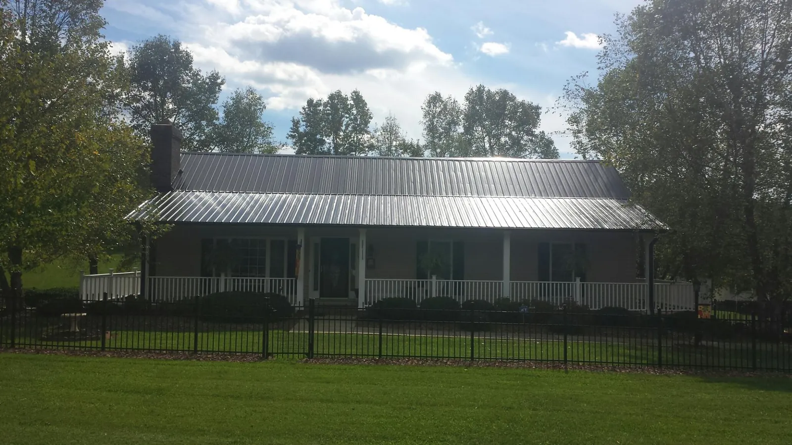 Gray metal roof on a brick ranch with a full width front porch — Gutter Guard Installation work by our crew in Elko
